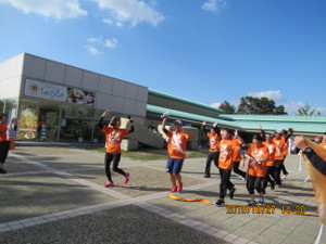 オレンジ色の服を着た人が湖水ホール前で走っている写真
