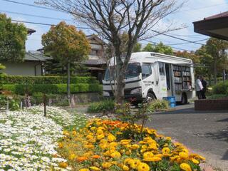 あおぞら号が花壇の近くに停まっている写真