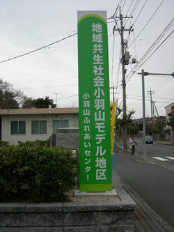 小羽山ふれあいセンター前に設置された「地域共生社会モデル地区」の看板の写真