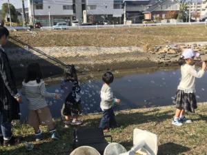 写真：川辺でシャボン玉を楽しむ子供たちの様子