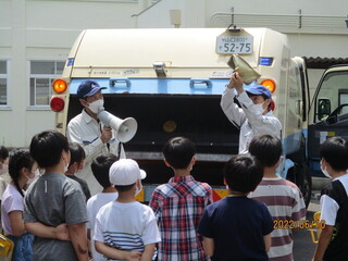 パッカー車の前でごみの分別の仕方を聞いている様子