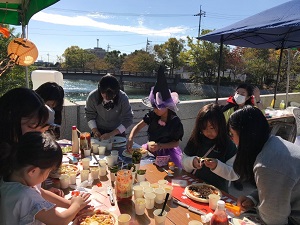 高校生のスタッフとハロウィンピザを作る子供達